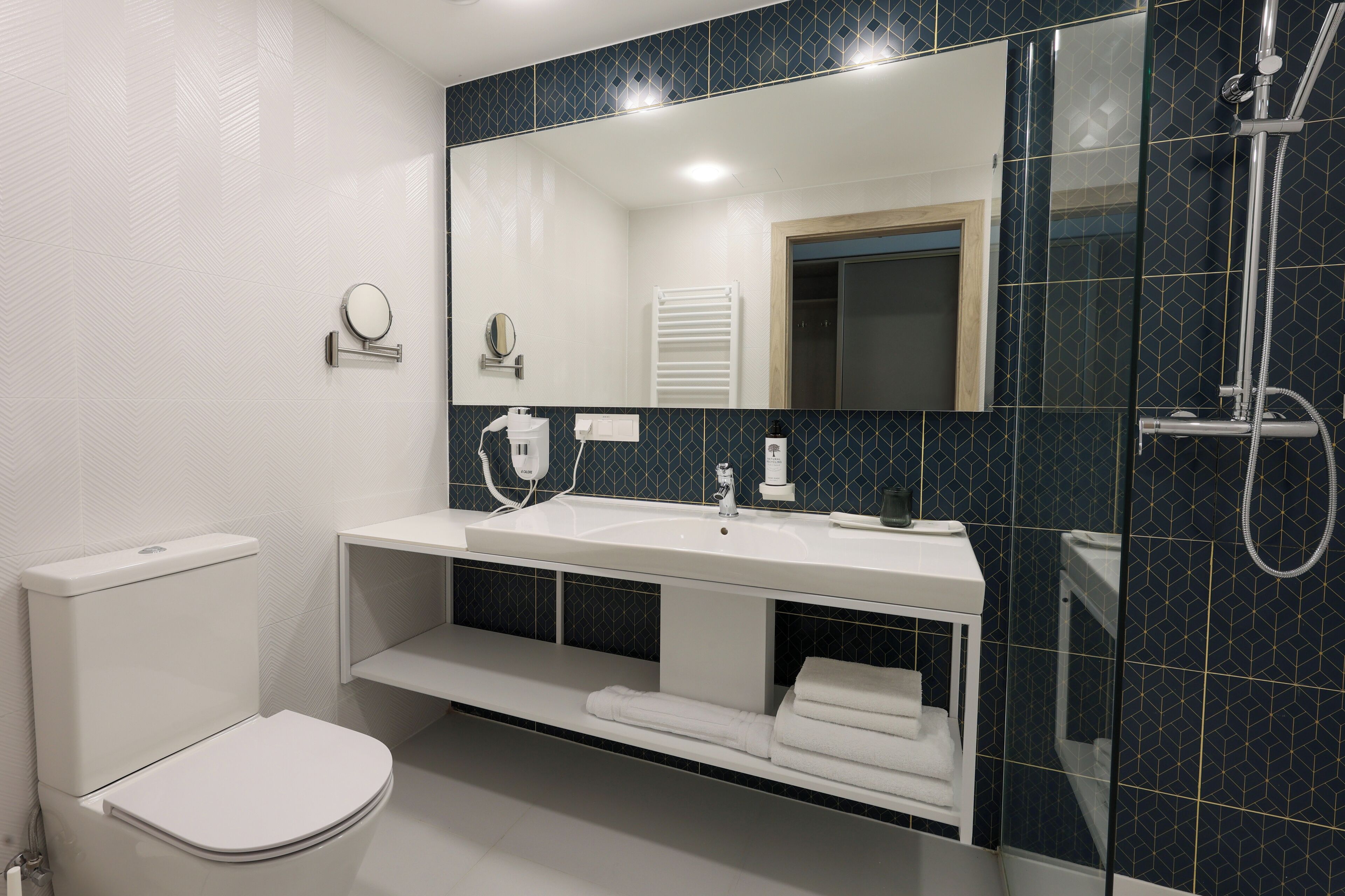 A modern bathroom with a white toilet, a sink with a mirror above it, and a shower area with a glass door.