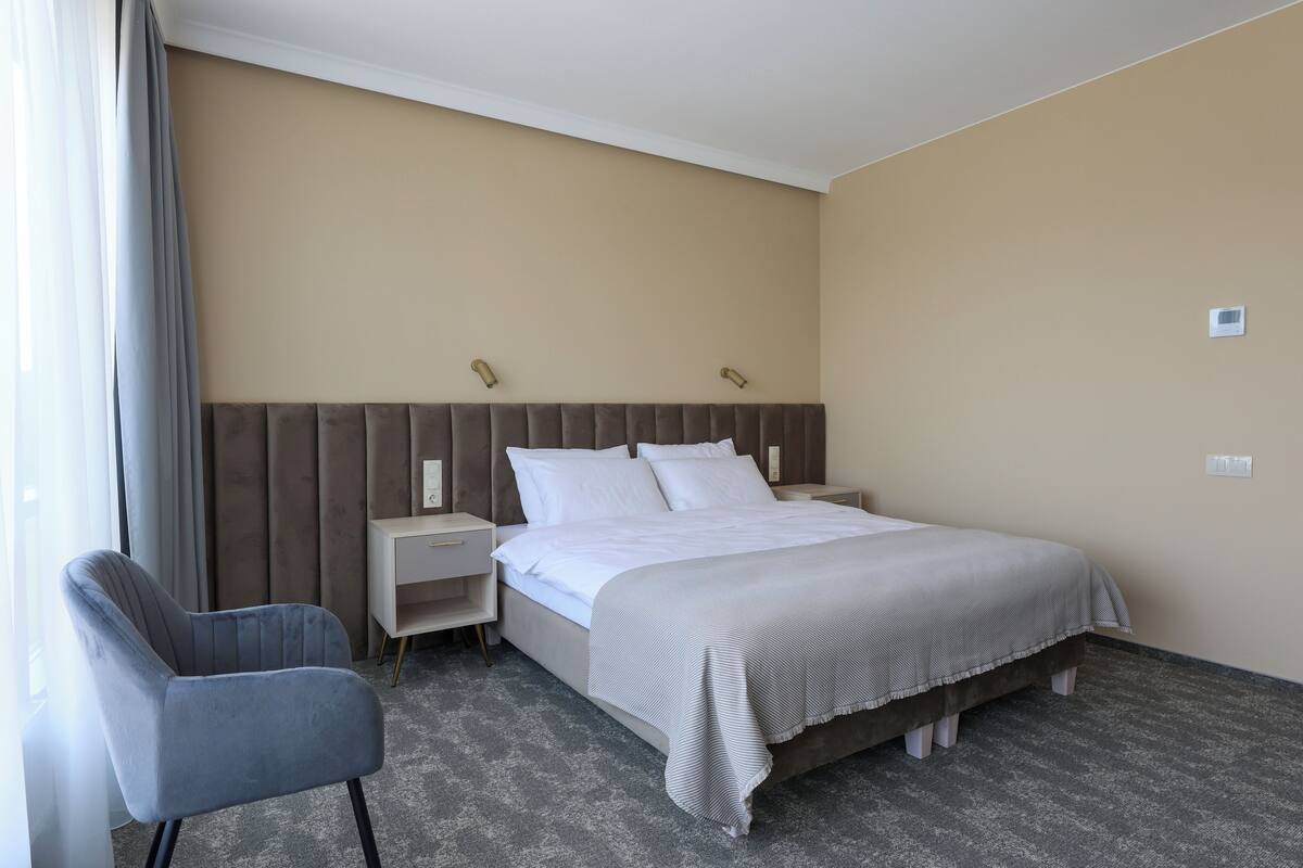 Ein Hotelzimmer mit einem Bett, einem Sessel, einem Nachttisch und einer Wandleuchte.