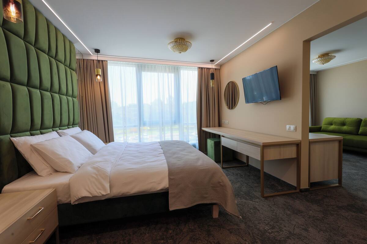 Ein Hotelzimmer mit Bett, Schreibtisch, Fernseher und einem grünen Sofa.