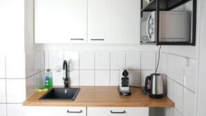 Una cocina con mostrador de madera, un lavamanos, un hervidor y un estante para especias.