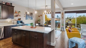 Une cuisine moderne avec des meubles de couleur bois foncé, un grand îlot central et des luminaires suspendus.