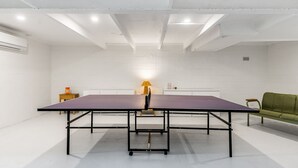 Ein Zimmer mit einem Tischtennis-Tisch, einem grünen Sofa und einer Lampe.