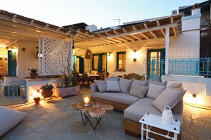 Un espace extérieur aménagé avec un canapé, des tables et des plantes en pot.