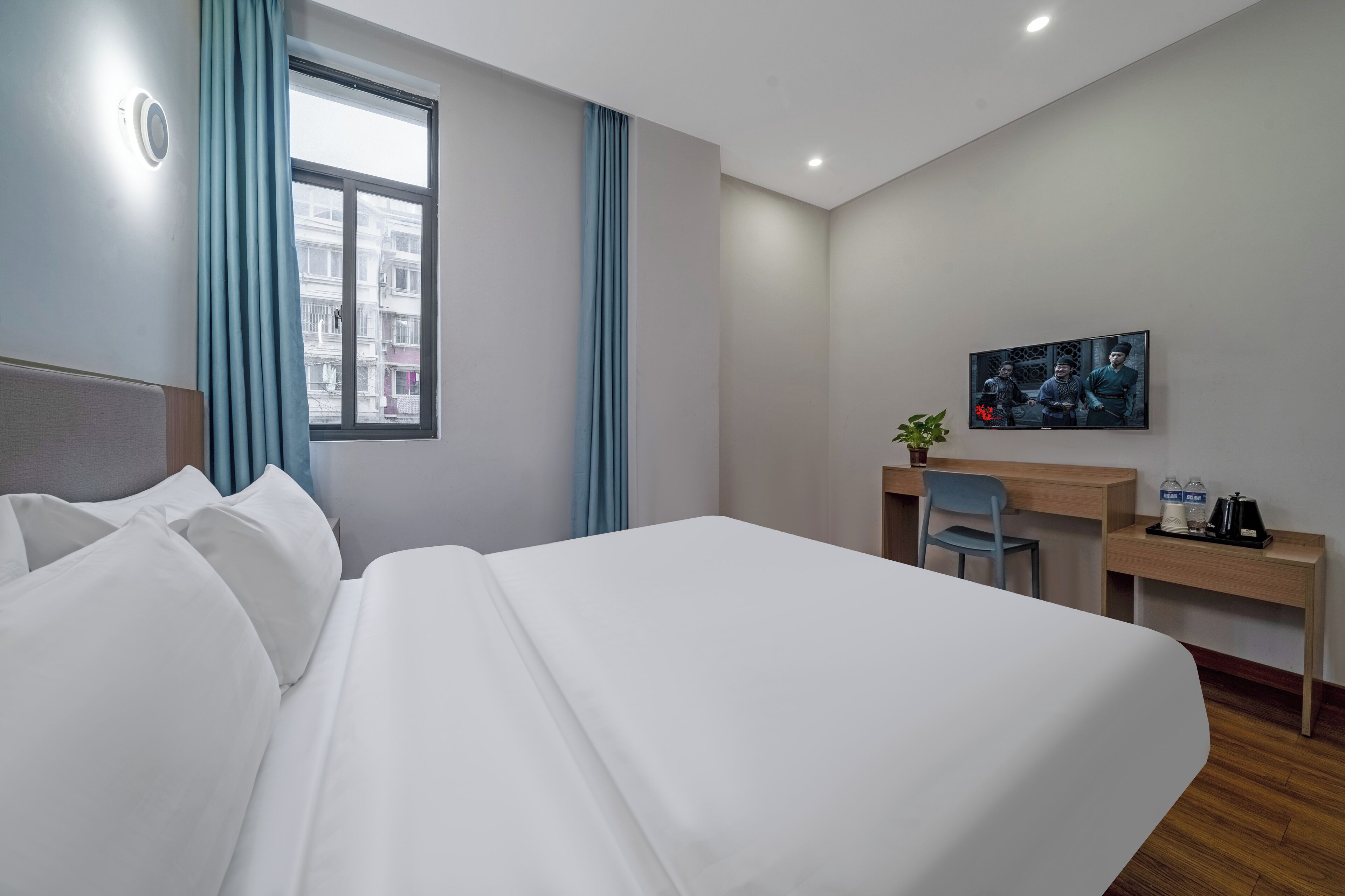 Une chambre d’hôtel avec un grand lit, un bureau, une chaise et une fenêtre avec des rideaux.