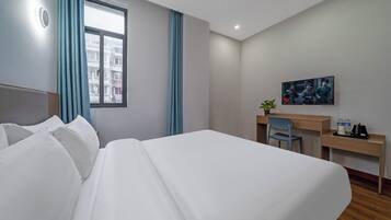 Une chambre d’hôtel avec un grand lit, un bureau, une chaise et une fenêtre avec des rideaux.