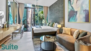 A modern hotel suite with a bed, a sofa, a dining area, and a large window offering a view of the city. - Vibrant & Exclusive Pool View Studio in Autograph (Dubai)