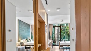 A modern hotel room with a bed, seating area, and a view of greenery outside. - Vibrant & Exclusive Pool View Studio in Autograph (Dubai)