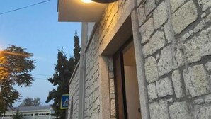 Ein Schild mit der Aufschrift 'KIRCAK KONAK ALACATI' an einem Gebäude mit Steinwänden und einem Fenster mit Vorhang.