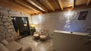 Ein gemütlicher Raum mit Steinwand, einer Rezeption, einer Couch und zwei Sesseln.