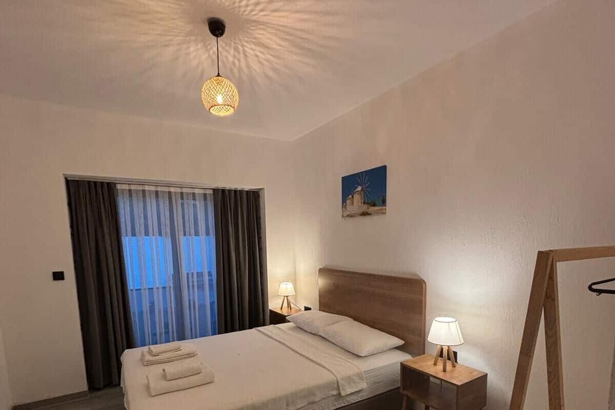 Une chambre d’hôtel avec un lit, une table de chevet, une lampe, un tableau et une échelle en bois.