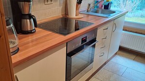 Uma cozinha com bancada de madeira, cafeteira, fogão e pia.