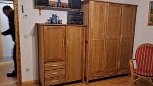 Quarto com móveis de madeira, incluindo um guarda-roupa com gavetas e uma cadeira.