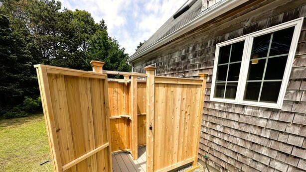 Un abri de jardin en bois, avec une porte, une fenêtre et un chemin de gravier menant à l’entrée.