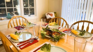 Une table à manger dressée avec des assiettes, des couverts, des verres et un centre de table composé de légumes et de fruits de mer.