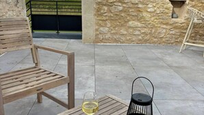 Eine Terrasse im Freien mit einem Holztisch, zwei Weingläsern, einem Metalllaternen und einer Steinmauer.