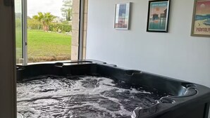 Ein Whirlpool mit Blick auf eine grüne Rasenfläche und Palmen.