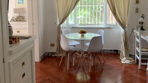 Un coin repas avec une table ronde, des chaises blanches et un ventilateur de plafond.