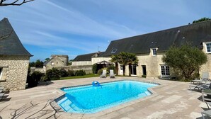 Una piscina amb gandules, edificis de pedra i un cel serè.