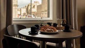 A round table with a plate of croissants, a coffee maker, and several black cups. - Moment George IV Bridge (Edinburgh)