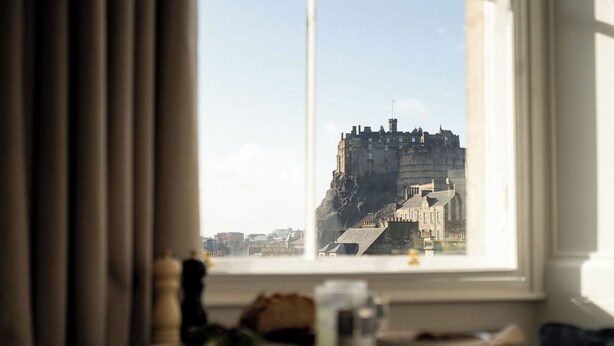 A view of a castle through a window, with a table and some items in the foreground. - Moment George IV Bridge (Edinburgh)