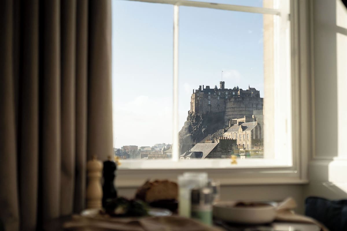 A view of a castle through a window, with a table and some items in the foreground.