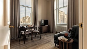 A modern hotel room with a dining area, a sofa, and a TV. - Moment George IV Bridge (Edinburgh)
