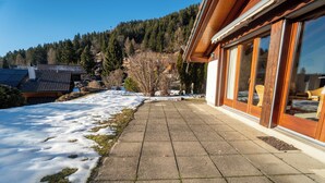 Un sendero cubierto de nieve que lleva a un edificio con grandes ventanales y fachada de madera.