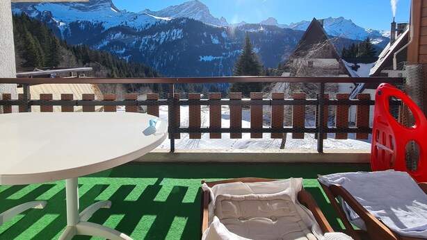A balcony with a view of snow-capped mountains, a table, and a chair. - The flat is located above the village of Gryon, in Les Verneys Soleil, 2 km from the Fracherets ski (Gryon)
