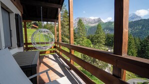 A wooden deck with a hanging spherical chair, a table, and a view of a mountainous landscape. - Charming apartment located in Les Arsets approx. 1 km from the start of the Fracherets ski lift link (Gryon)