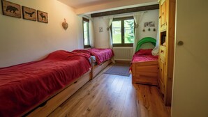 A cozy room with two wooden beds, a wooden wardrobe, and a window with curtains. - Charming apartment located in Les Arsets approx. 1 km from the start of the Fracherets ski lift link (Gryon)