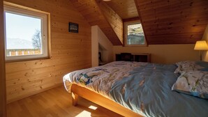 A wooden-paneled bedroom with a bed, a window, and a ceiling light.