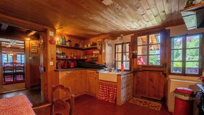 A rustic wooden kitchen with a red tiled floor, wooden cabinets, and a window overlooking a garden. - This beautiful chalet built in 1872 is located in the heart of the pretty village of Gryon. Gryon tr (Gryon)