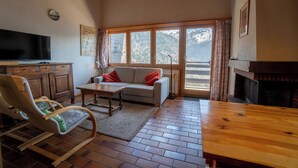 Una sala de estar con un sofá, una mesa de madera, un televisor y una chimenea.