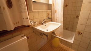 Un baño con lavamanos, espejo, cortina de ducha y bañera.