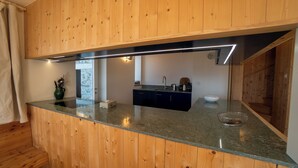 A modern kitchen with wooden cabinetry and a granite countertop. - The chalet, which has just been renovated in 2024, is located 200m from the ski slope linking the Vi (Gryon)