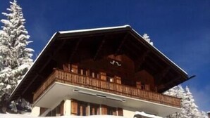 A chalet with a wooden balcony, surrounded by snow-covered trees. - The chalet, which has just been renovated in 2024, is located 200m from the ski slope linking the Vi (Gryon)