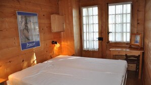 A wooden room with a bed, a desk, and a window.