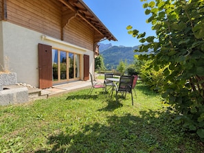 Une maison en bois avec une terrasse, une table et des chaises.