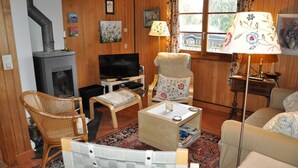 Una sala de estar acogedora con chimenea, televisor, asientos cómodos y un tapete estampado.