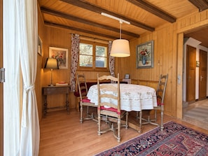 Una habitación con paneles de madera, una mesa redonda, sillas, una lámpara y una alfombra.