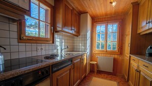 Una cocina con armarios de madera, salpicadero de azulejos, estufa y ventana con vistas a árboles.