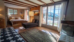 Un dormitorio acogedor con cama, sofá, ventana grande con vistas y chimenea.