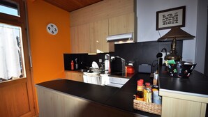 Une cuisine avec des meubles de rangement en bois, un plan de travail noir, une horloge et un tableau encadré au mur.