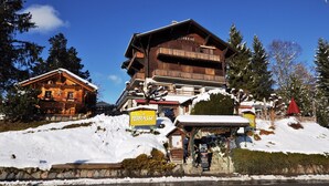 Un chalet en bois doté d’un balcon, entouré d’un paysage enneigé et d’arbres.
