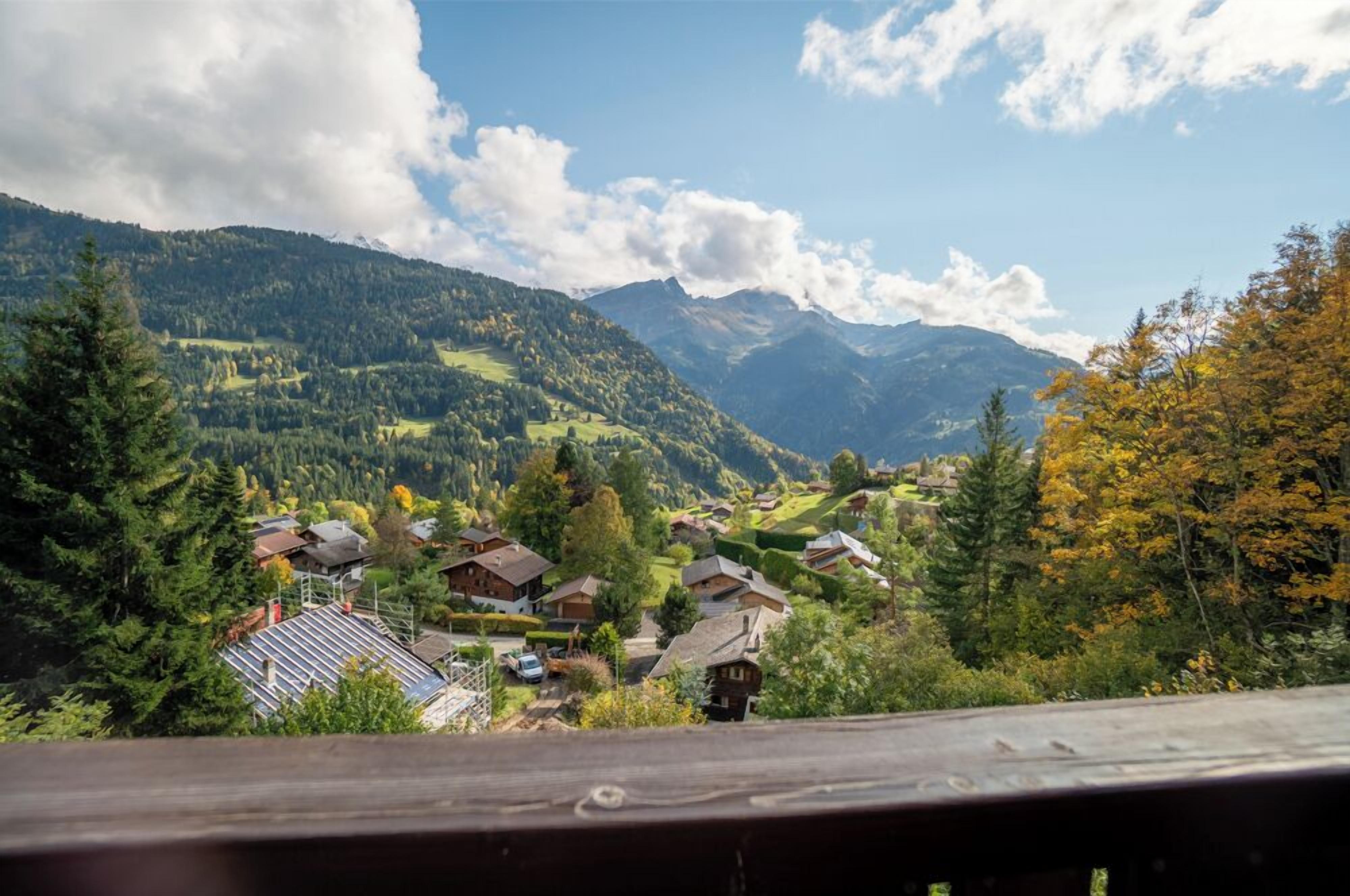A mountain village with traditional houses, a clear sky, and a view of the surrounding hills.