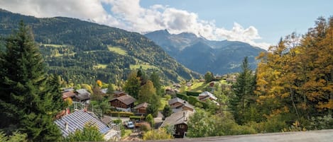 A mountain village with traditional houses, a clear sky, and a view of the surrounding hills.