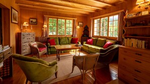 Interior acogedor de una cabaña de madera con un sofá verde, una mesa de comedor y una estantería.