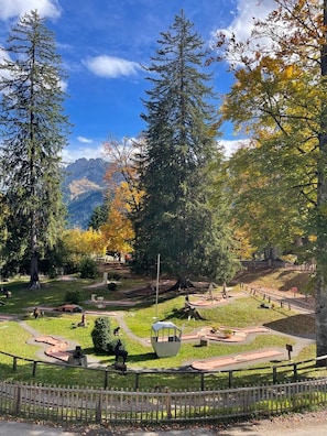 A park with a clear sky, autumn trees, and a sculpture in the center.