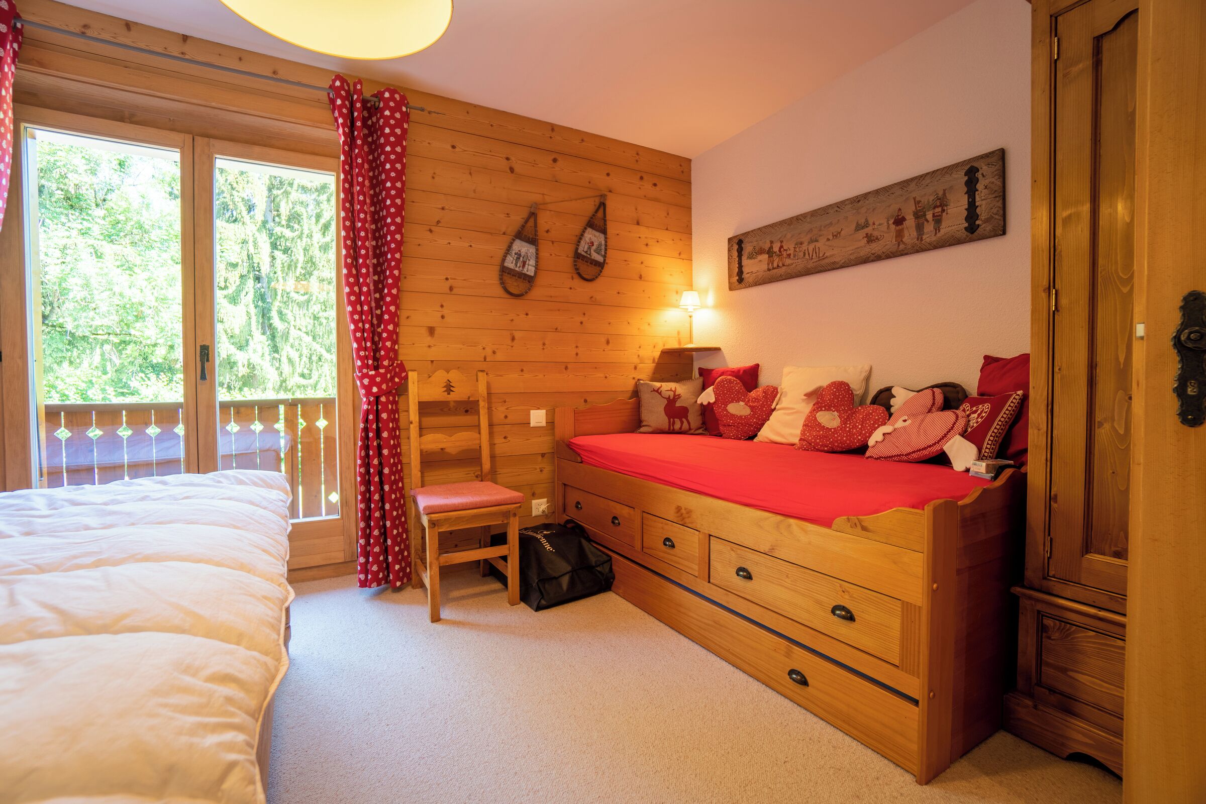 A wooden bedroom with a bed, a chair, a dresser, and a window with curtains.