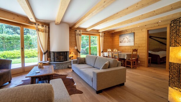 A cozy living room with a sofa, a coffee table, and a fireplace. There is a dining area with a table and chairs.